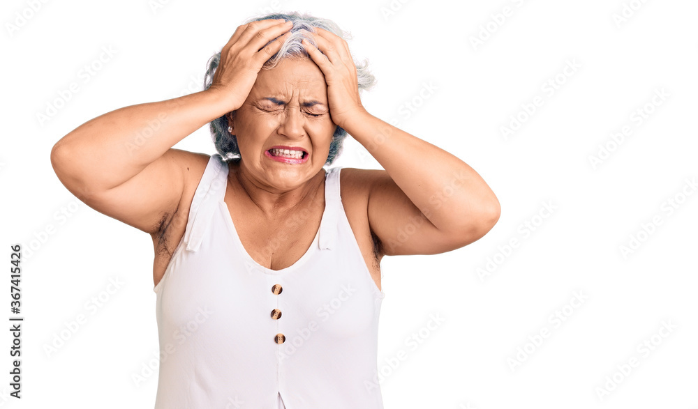 Senior woman with gray hair wearing casual clothes suffering from headache desperate and stressed because pain and migraine. hands on head. Senior woman with gray hair wearing casual clothes suffering from headache desperate and stressed because pain and migraine. hands on head.