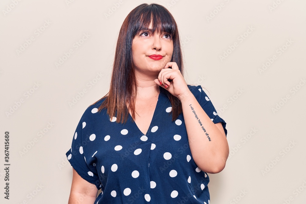 Young plus size woman wearing casual clothes serious face thinking about question with hand on chin, thoughtful about confusing idea Young plus size woman wearing casual clothes serious face thinking about question with hand on chin, thoughtful about confusing idea