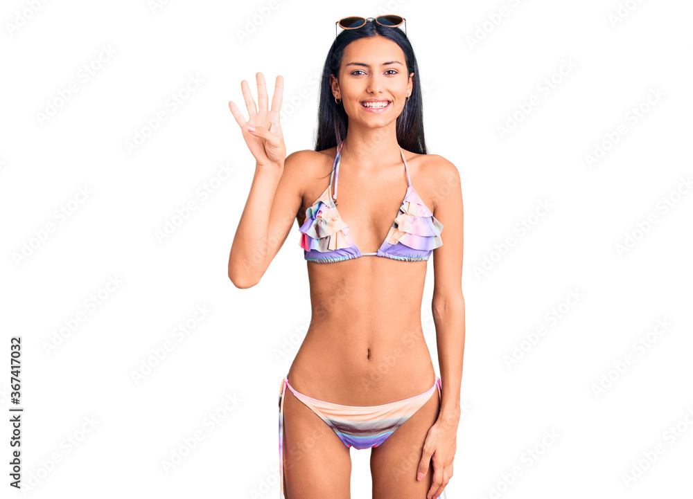 Young beautiful latin girl wearing bikini and sunglasses showing and pointing up with fingers number four while smiling confident and happy. Young beautiful latin girl wearing bikini and sunglasses showing and pointing up with fingers number four while smiling confident and happy.