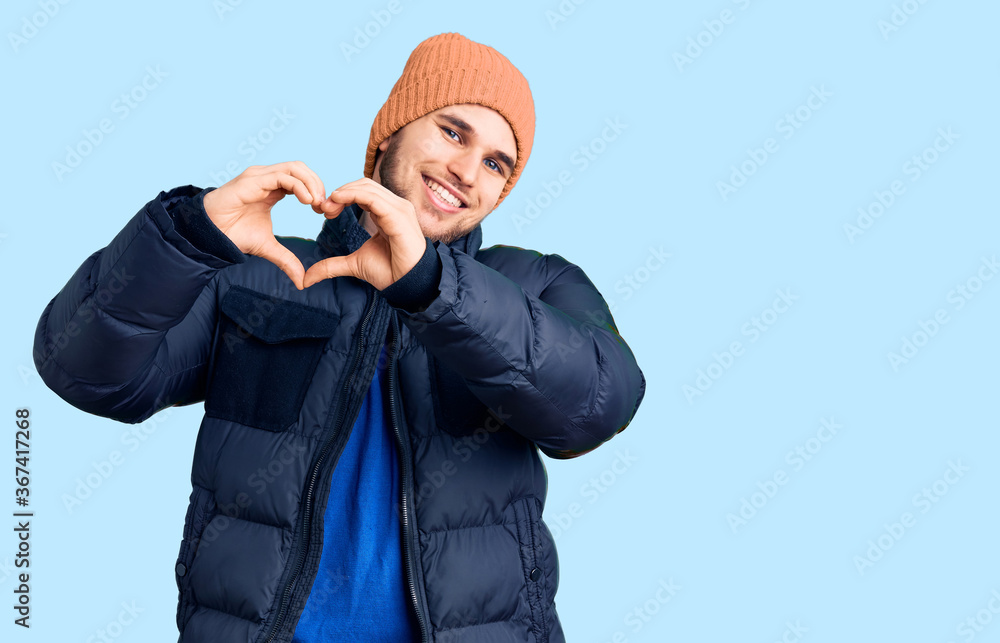 Young handsome man wearing winter clothes smiling in love showing heart symbol and shape with hands. romantic concept. Young handsome man wearing winter clothes smiling in love showing heart symbol and shape with hands. romantic concept.