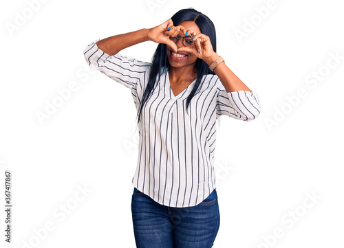 Young african american woman wearing casual clothes and glasses doing heart shape with hand and fingers smiling looking through sign