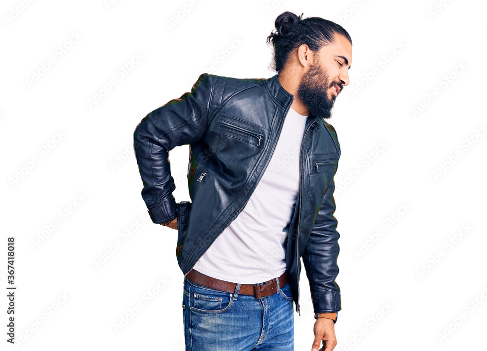 Young arab man wearing casual leather jacket suffering of backache, touching back with hand, muscular pain Young arab man wearing casual leather jacket suffering of backache, touching back with hand, muscular pain