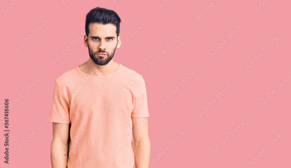 Young handsome man with beard wearing casual t-shirt skeptic and nervous, frowning upset because of problem. negative person. Young handsome man with beard wearing casual t-shirt skeptic and nervous, frowning upset because of problem. negative person.