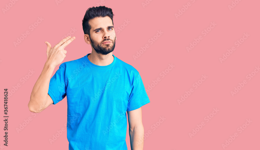 Young handsome man with beard wearing casual t-shirt shooting and killing oneself pointing hand and fingers to head like gun, suicide gesture. Young handsome man with beard wearing casual t-shirt shooting and killing oneself pointing hand and fingers to head like gun, suicide gesture.