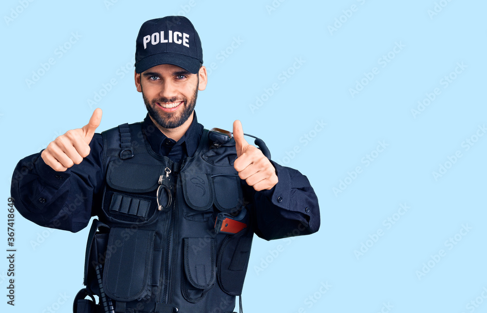 Young handsome man with beard wearing police uniform approving doing positive gesture with hand, thumbs up smiling and happy for success. winner gesture. Young handsome man with beard wearing police uniform approving doing positive gesture with hand, thumbs up smiling and happy for success. winner gesture.