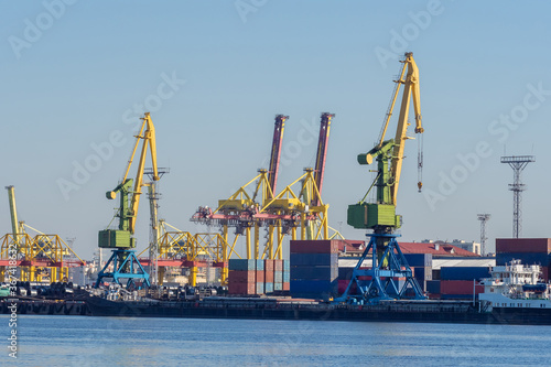 Sea commercial port. Loading and unloading operations in the port. Cranes and cargo containers on the shore. Merchant fleet. Shipping.
