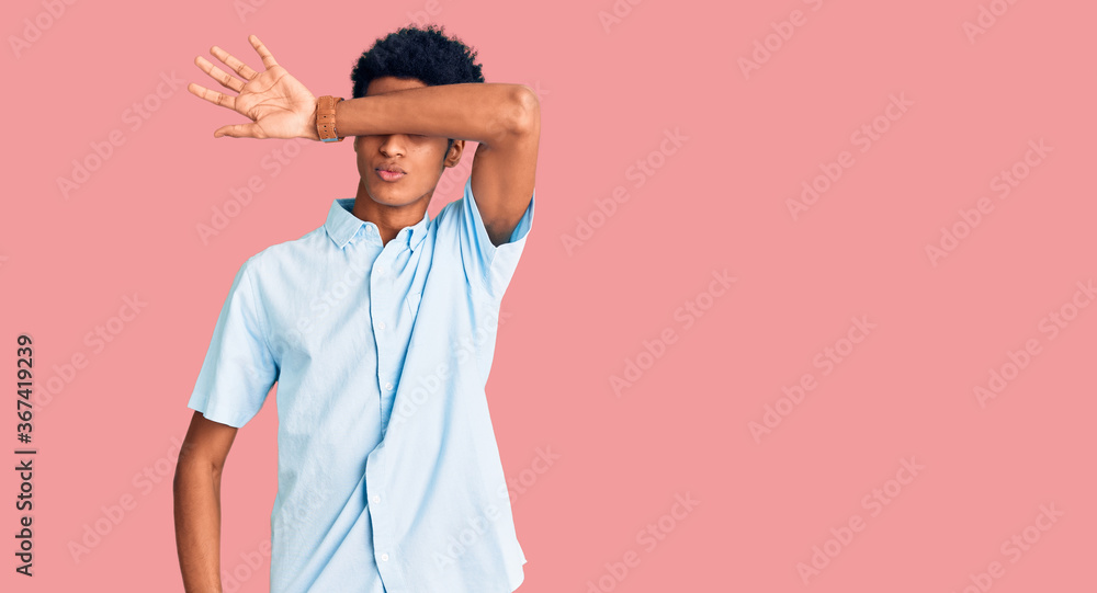 Young african american man wearing casual clothes covering eyes with arm, looking serious and sad. sightless, hiding and rejection concept Young african american man wearing casual clothes covering eyes with arm, looking serious and sad. sightless, hiding and rejection concept
