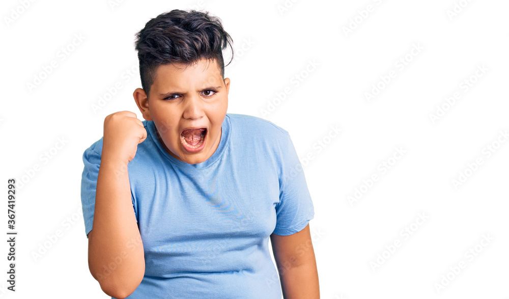 Little boy kid wearing sports workout clothes angry and mad raising fist frustrated and furious while shouting with anger. rage and aggressive concept. Little boy kid wearing sports workout clothes angry and mad raising fist frustrated and furious while shouting with anger. rage and aggressive concept.