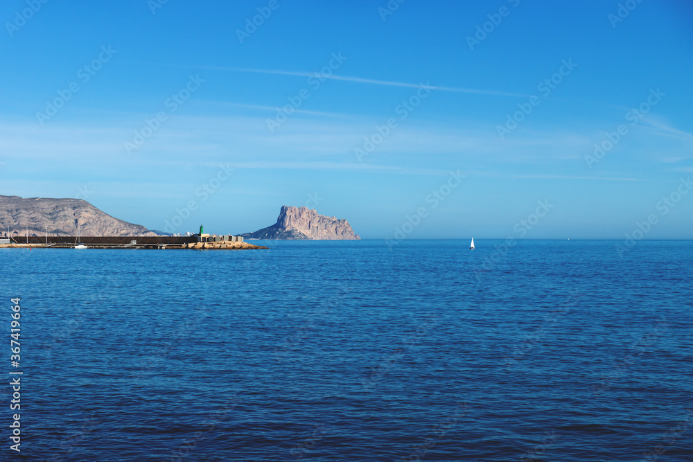 Panoramic view over the blue ocean to the rock of Calpe with sailboat, Costa Blanca, Spain