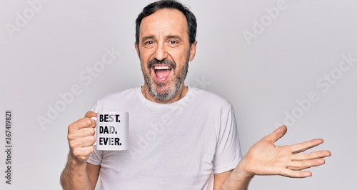 Middle age handsome man drinking cup of coffee with best dad ever message celebrating achievement with happy smile and winner expression with raised hand