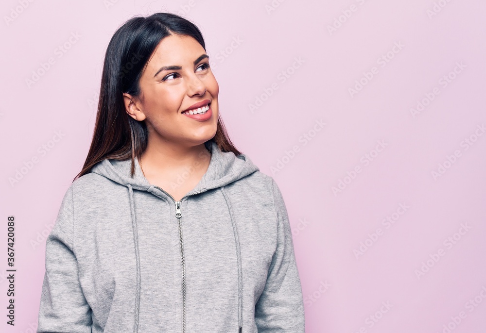 Young beautiful sporty woman wearing sportswear standing over isolated pink background looking to side, relax profile pose with natural face and confident smile. Young beautiful sporty woman wearing sportswear standing over isolated pink background looking to side, relax profile pose with natural face and confident smile.