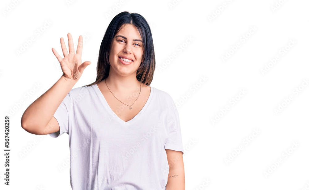 Young beautiful brunette woman wearing casual t-shirt showing and pointing up with fingers number five while smiling confident and happy. Young beautiful brunette woman wearing casual t-shirt showing and pointing up with fingers number five while smiling confident and happy.