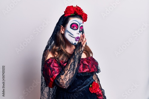 Young woman wearing day of the dead costume over white hand on mouth telling secret rumor, whispering malicious talk conversation © Krakenimages.com