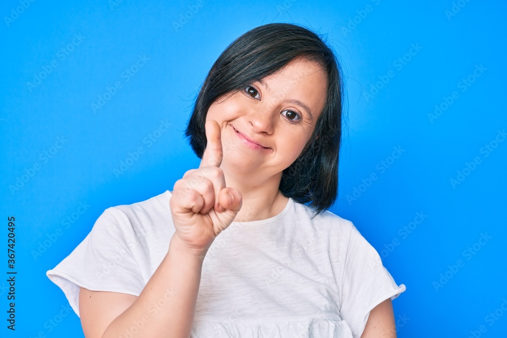 Brunette woman with down syndrome wearing casual clothes smiling with an idea or question pointing finger up with happy face, number one Brunette woman with down syndrome wearing casual clothes smiling with an idea or question pointing finger up with happy face, number one