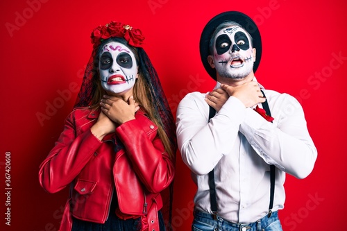 Couple wearing day of the dead costume over red shouting suffocate because painful strangle. health problem. asphyxiate and suicide concept. © Krakenimages.com