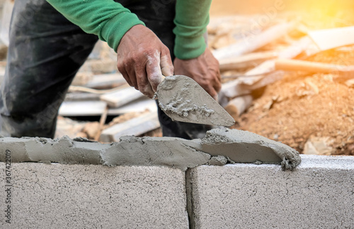 Foto Close up of a worker putting cement into the brick wall at construction site