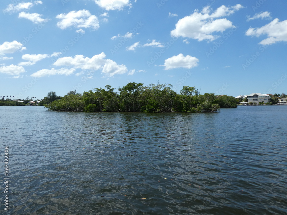 Island in large body of water with blue sky and clouds overhead