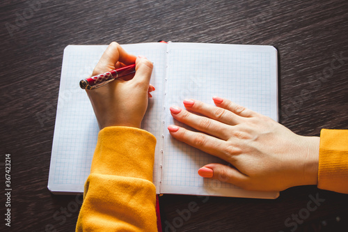 Young woman holds a pen in her left hand and writes  note in blank notebook. International Left-Handers Day photo