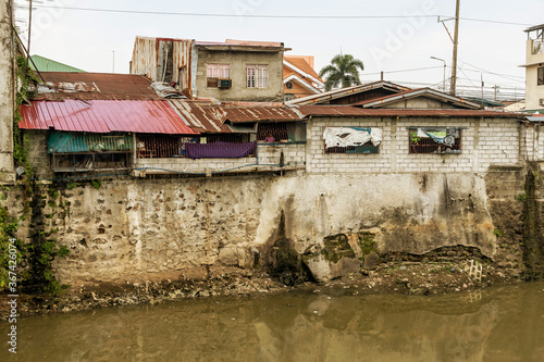A slum or squatter area along a heavily polluted river bordering Metro Manila and Cavite. Disregard of zoning laws near riverbanks. A polluted river.