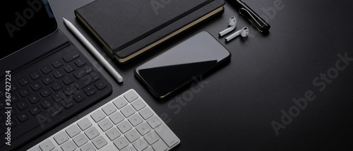 Digital devices with smartphone, tablet, keyboard, stationery, accessories and copy space on dark table photo