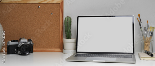 Home office desk with laptop, supplies, memory board and decorations on white table, clipping path.