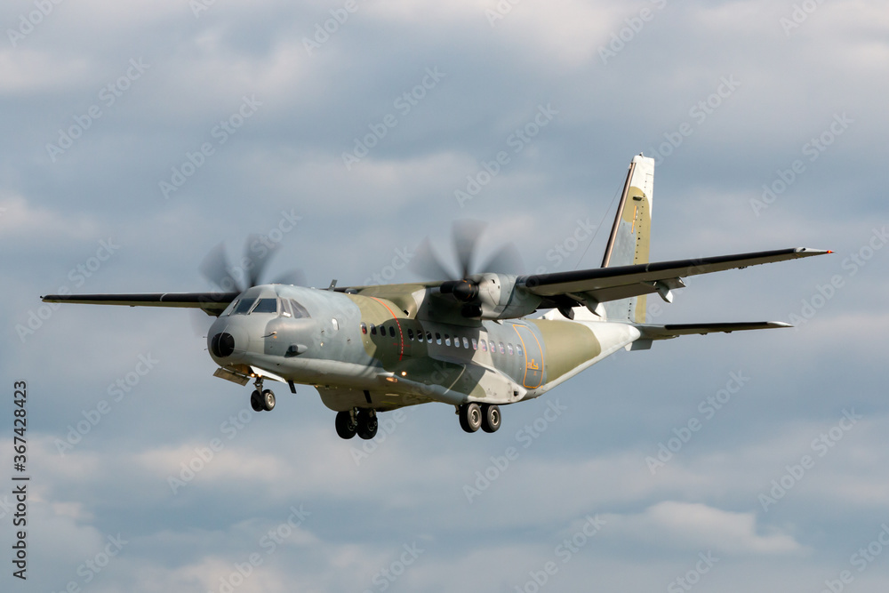 Obraz premium Twin engined camouflaged military cargo airplane on approach to land.