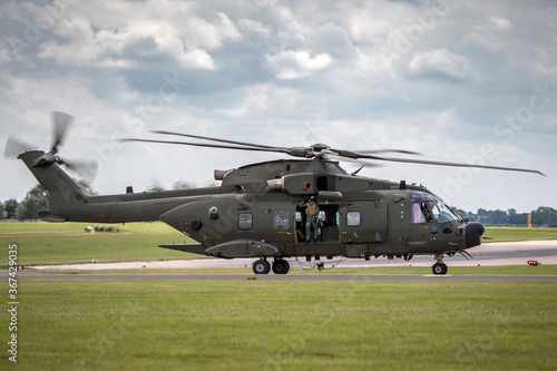 Large green army helicopter taxiing at an airbase after landing.