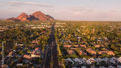 Aerial footage of Phoenix, Arizona  flying above Camelback Road and mountain glowing red in the evening sun.   photo