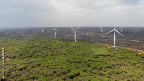 Aerial shot panning over a forest towards a wind farm in Barao de Sao Joao, Portugal. photo