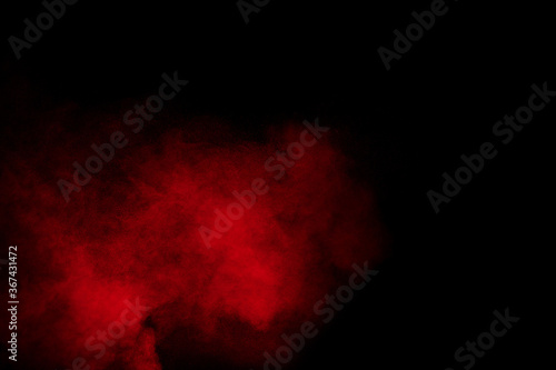 Red powder explosion cloud on black background. Freeze motion of red color dust particles splashing.