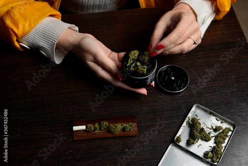 Fotótapéta Young woman with cigarrette smoking weed hands nails marijuana grinder