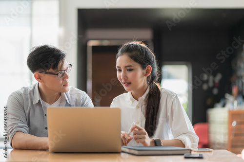 Asian business people man and woman conference talking and working with laptop together. Young couple work at home.