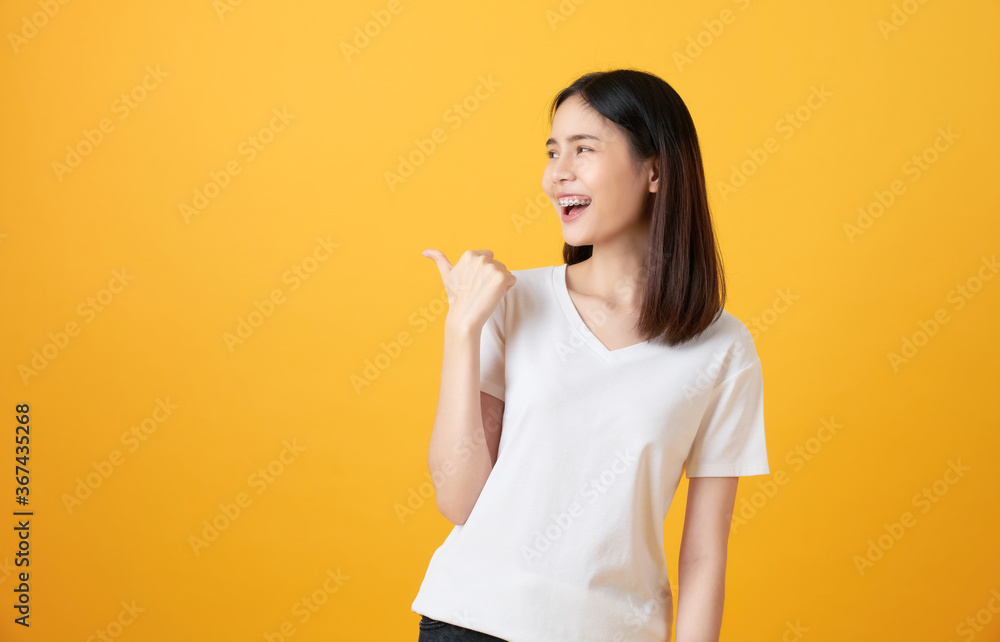 Smiling Asian woman stand and pointing finger on orange background. Smiling Asian woman stand and pointing finger on orange background.