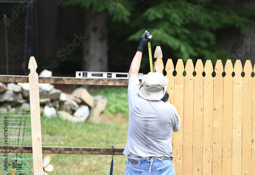 Canvas Print manual worker installing the wood fence in the yard