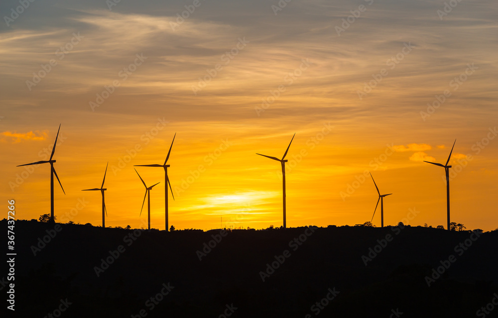 Fototapeta premium Silhouette wind turbine with twilight sky and sunlight ray for clean energy plant on the mountain.