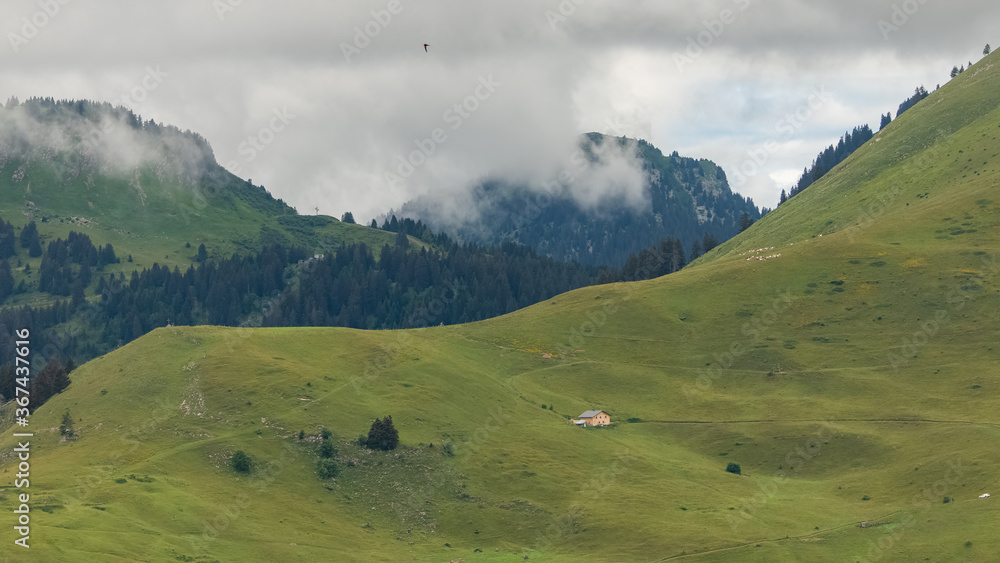 An isolated chalet in the Alps, near Morzine, in France, the mountain in spring, in the clouds
