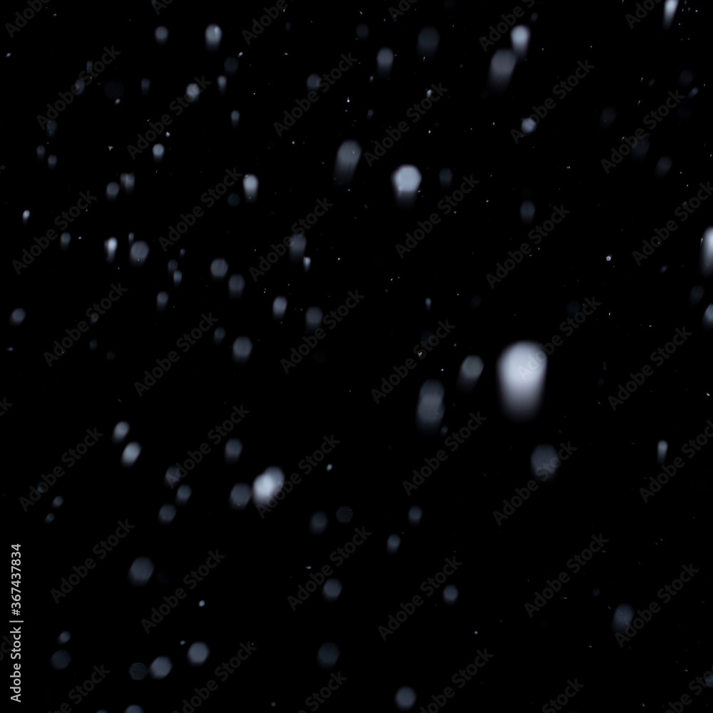 first snow in winter on black sky background, abstract blurred photo