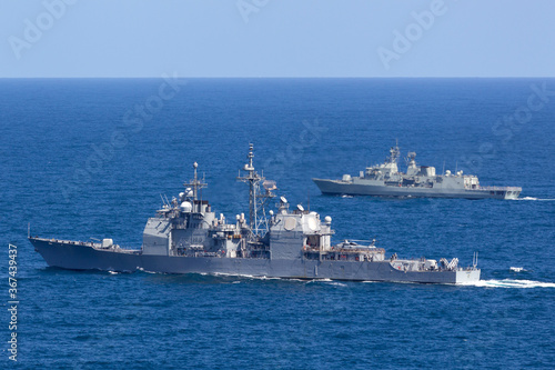 Two warships sailing out to sea during a military exercise.