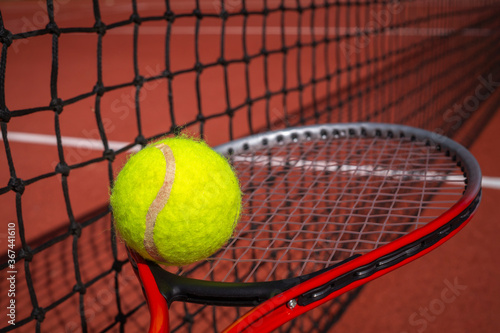 Tennis ball on a racket alongside a net © NetPix