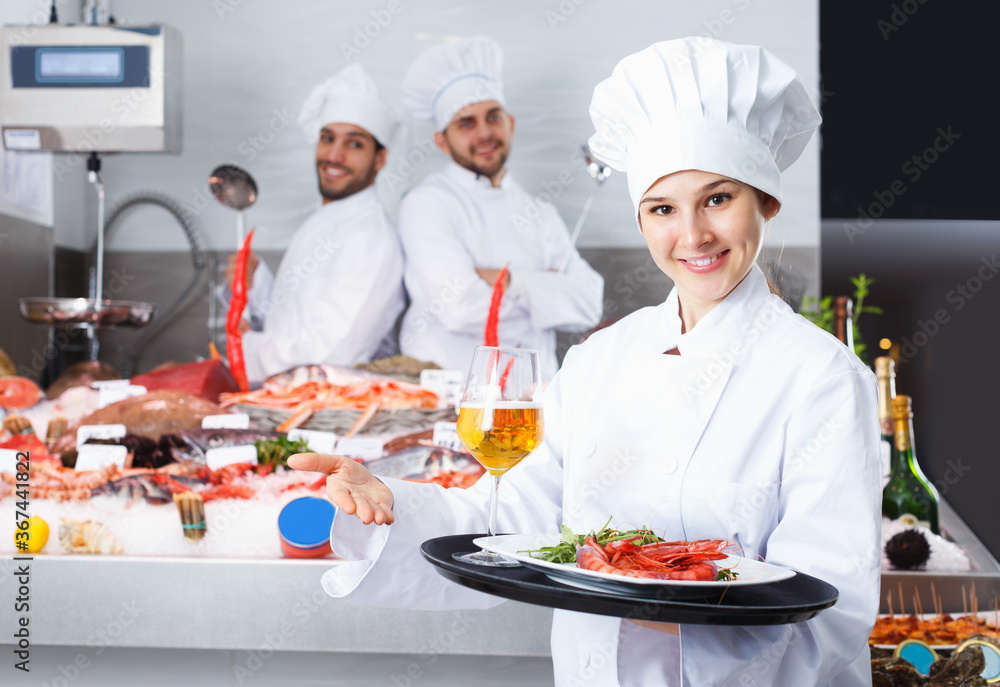 Portrait of confident woman chef standing with serving tray in fish restaurant