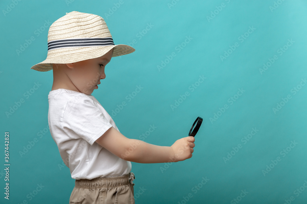 Close-up portrait of a cute boy looking through a magnifying glass-isolated on a blue background. Close-up portrait of a cute boy looking through a magnifying glass-isolated on a blue background.