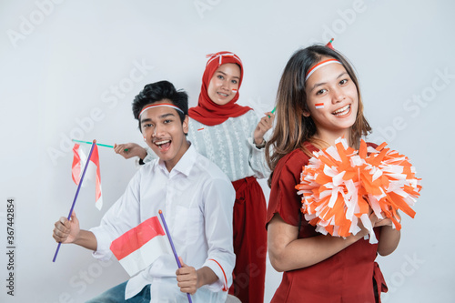group of teenage wearing red and white attributes carrying pompom and Indonesian small flags with isolated background