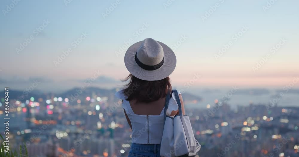 Woman tourist with straw hat and look at the city view at sunset time