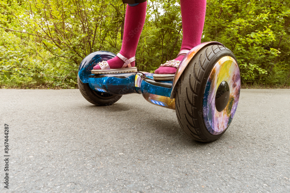 Legs of girl riding on self-balancing mini hoverboard in city Park.  Electronic scooter outdoors - personal portable eco transport, gyro scooter,  hyroscooter, smart balance wheel, m Photos | Adobe Stock