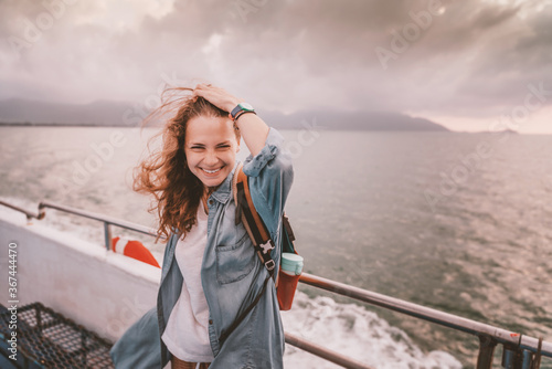 Stampa su tela Happy curly young woman traveler on a ship at the sea against the backdrop of a beautiful landscape