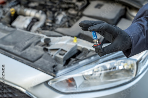 Repair man hand installing halogen led bulb for car headlights