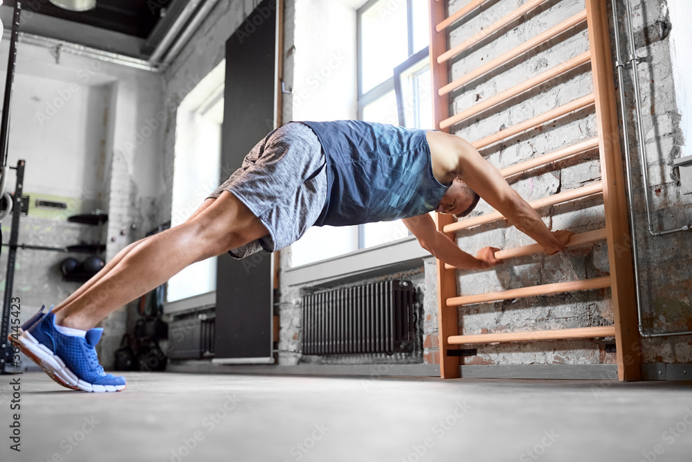 sport, bodybuilding, fitness and people concept - young man exercising on gymnastics wall bars in gym sport, bodybuilding, fitness and people concept - young man exercising on gymnastics wall bars in gym