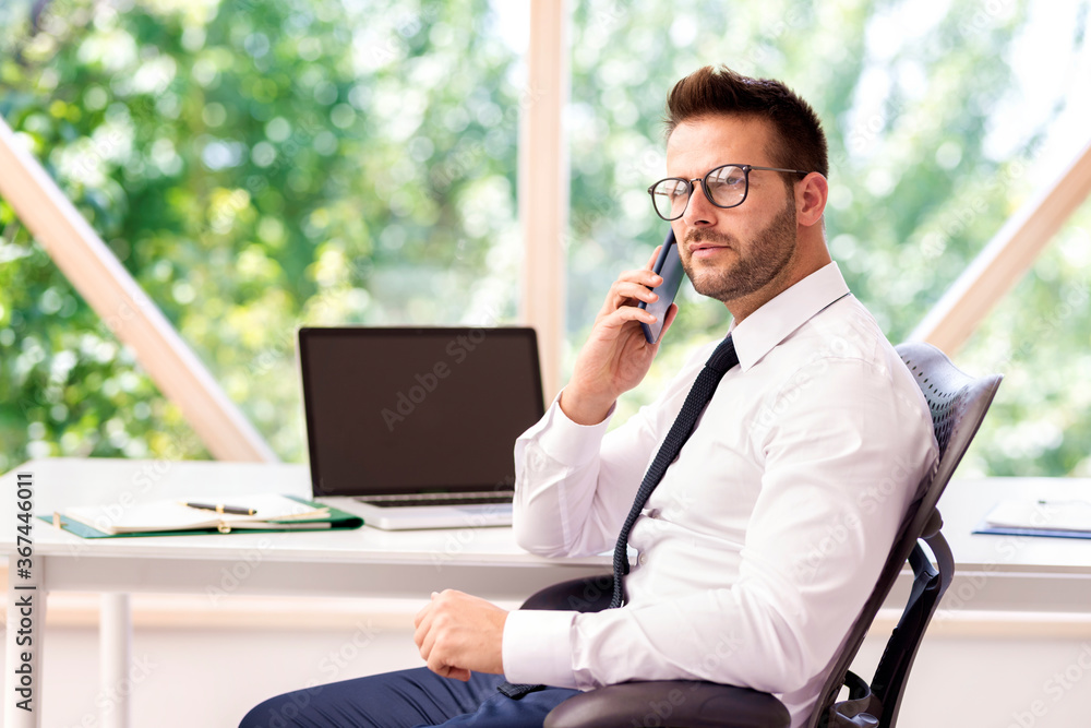 Businessman making a call while sitting at office desk Businessman making a call while sitting at office desk