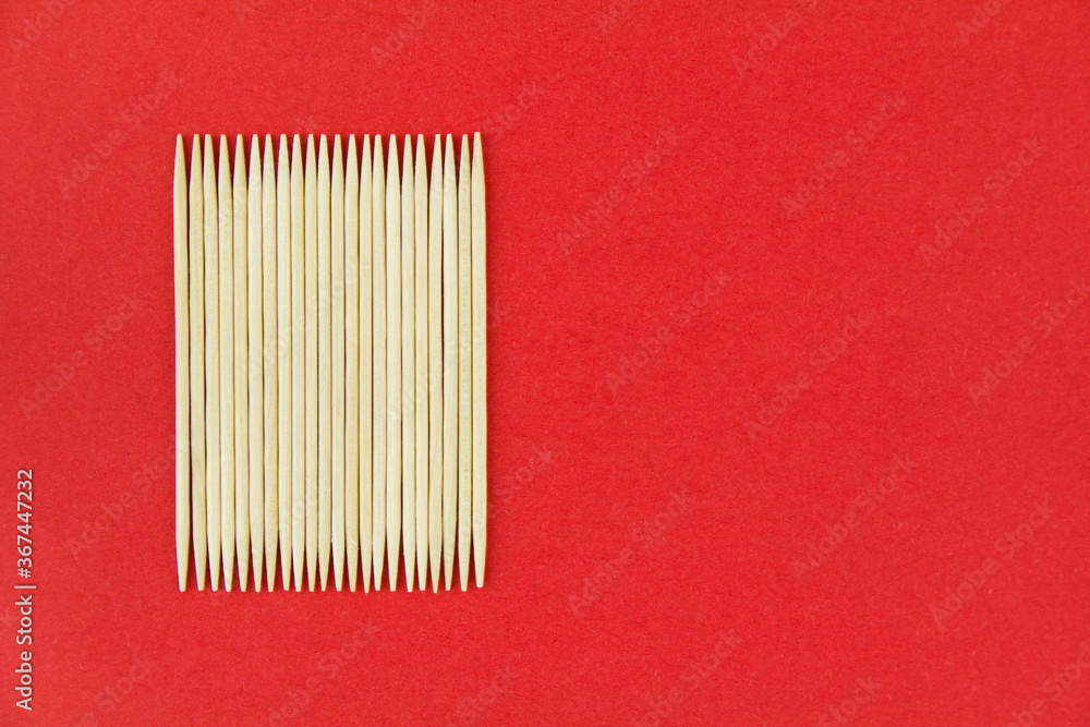 Wooden toothpicks on red paper background. Copy space for text. Wooden toothpicks on red paper background. Copy space for text.
