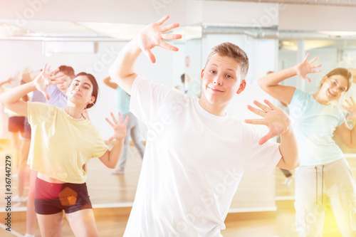 Teenagers in dance hall studying new movements, smiling and having fun © JackF